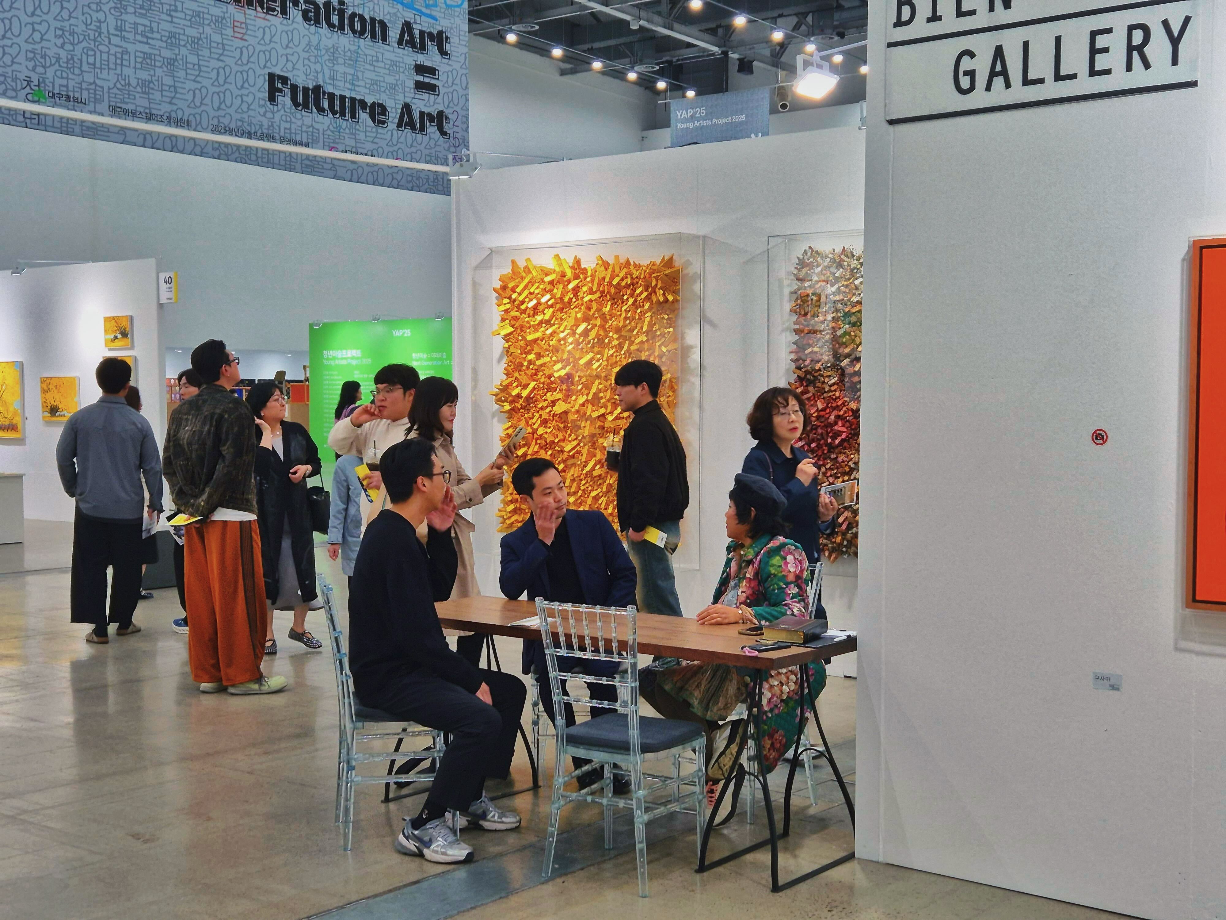 Korean art fair gallery booth with visitors and artworks